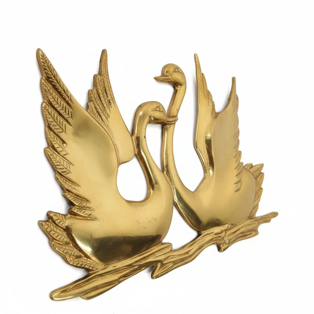 Gold emblem with two swans on a branch against a white background