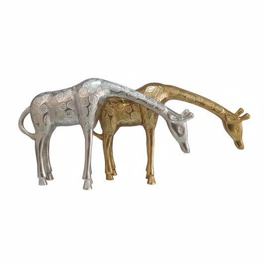 Two giraffe figurines, one silver and one gold, on a light gray surface.