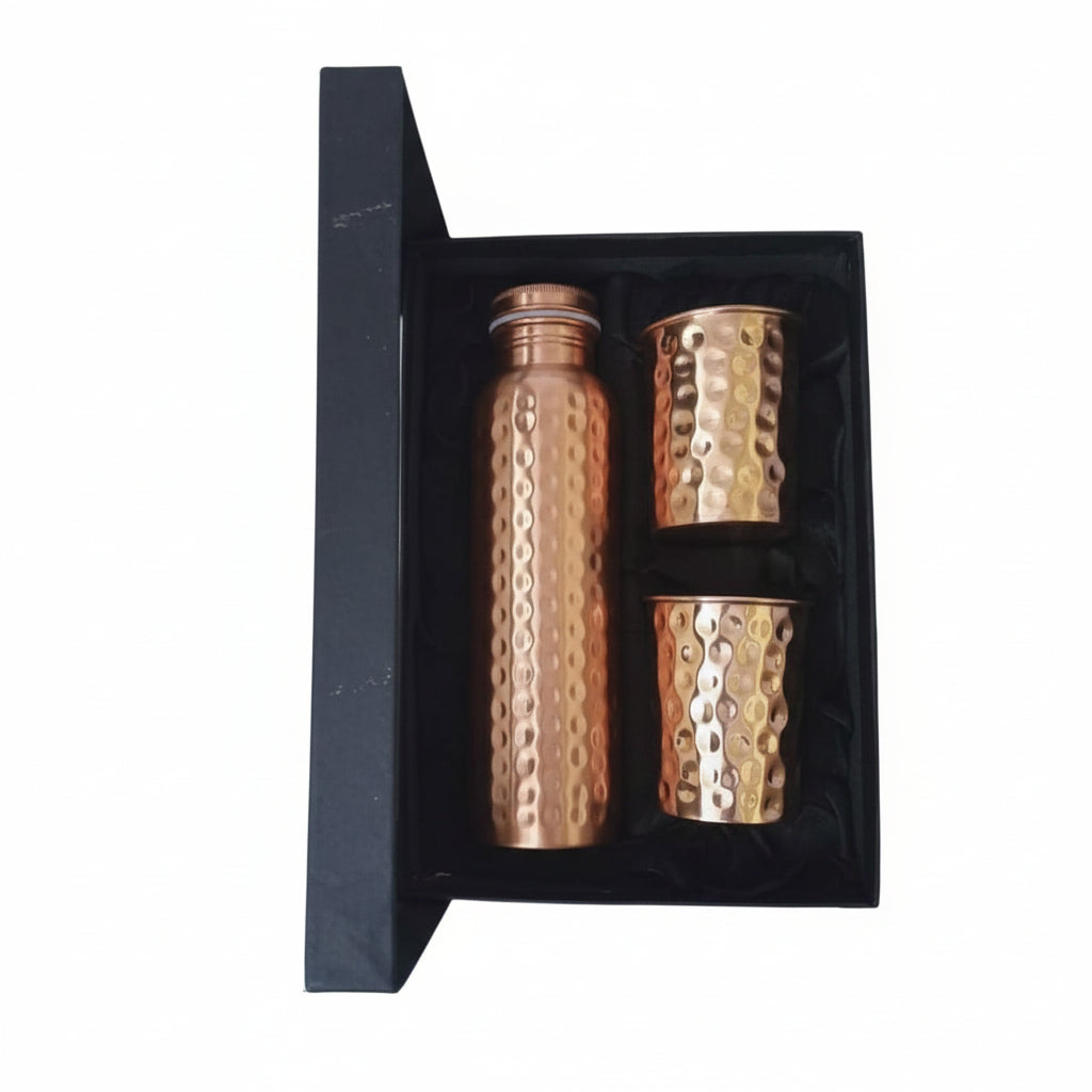 Copper water bottle and cups set in a black box on a light gray background
