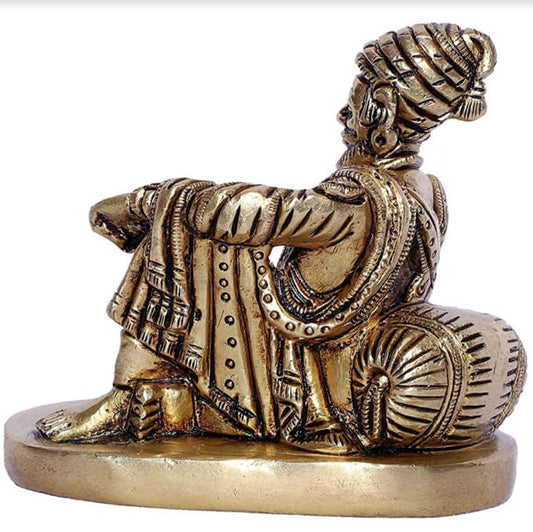 Bronze statue of a seated figure with intricate details on a white background