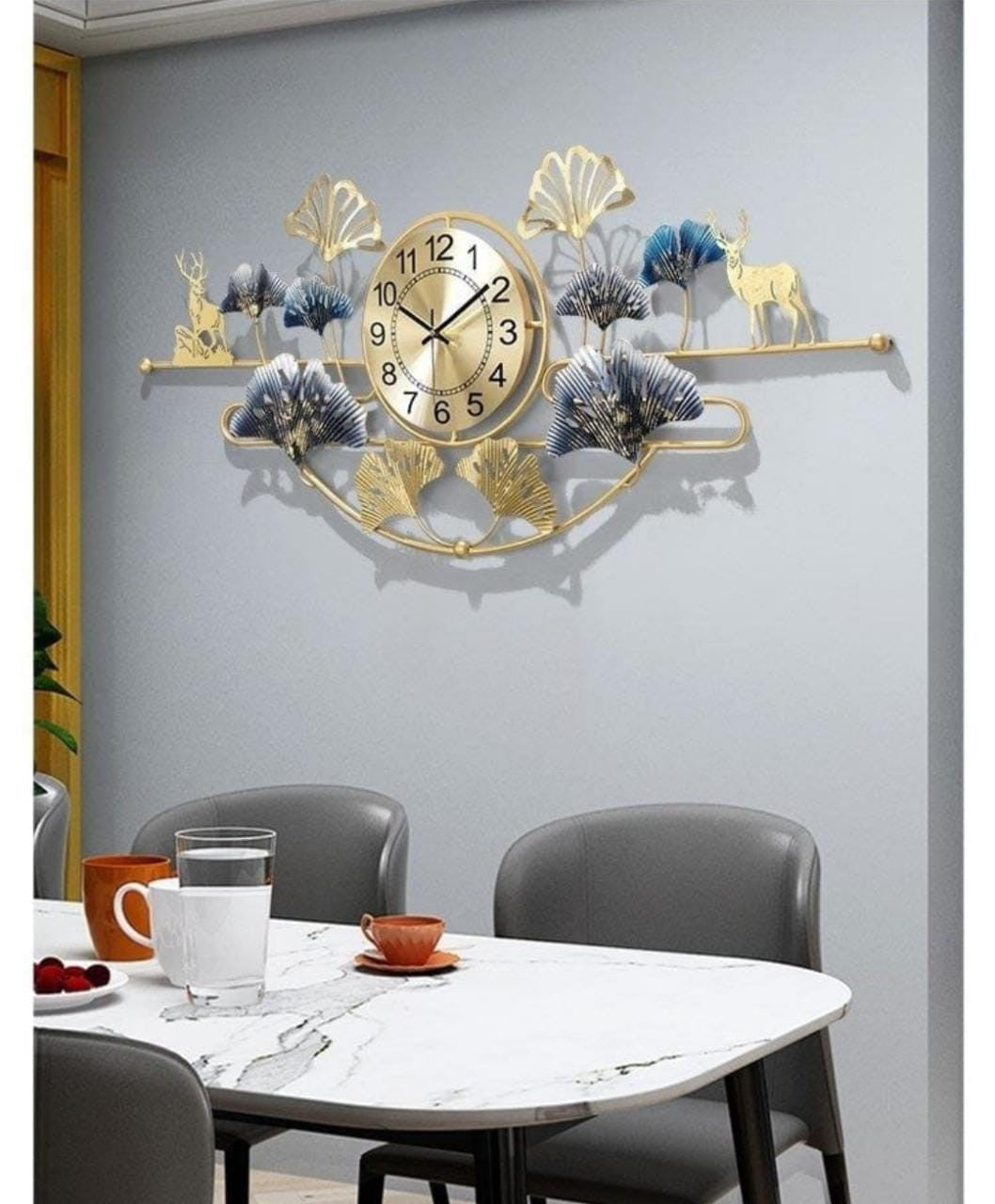 Decorative wall clock with floral and deer design on a gray wall above a dining table.