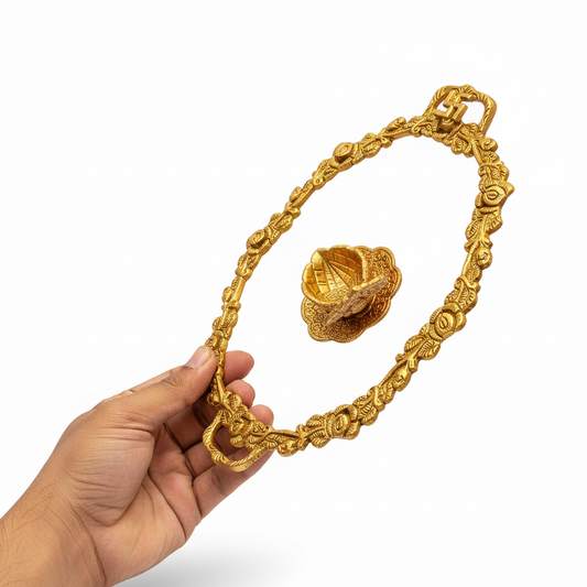 Gold necklace with intricate design held by a hand on a white background