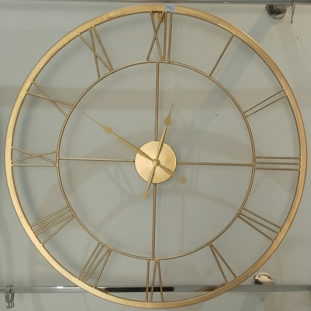 Gold wall clock with Roman numerals on a light background