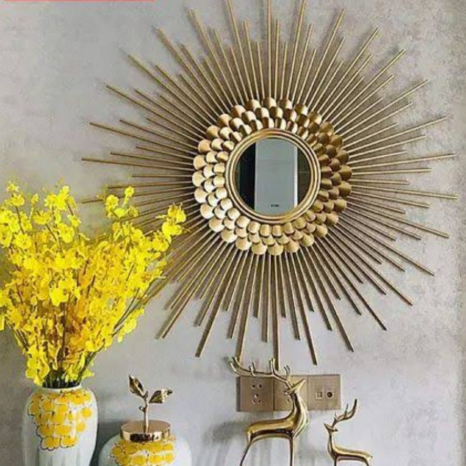Decorative gold sunburst mirror on a wall with yellow flowers and small decorative items.