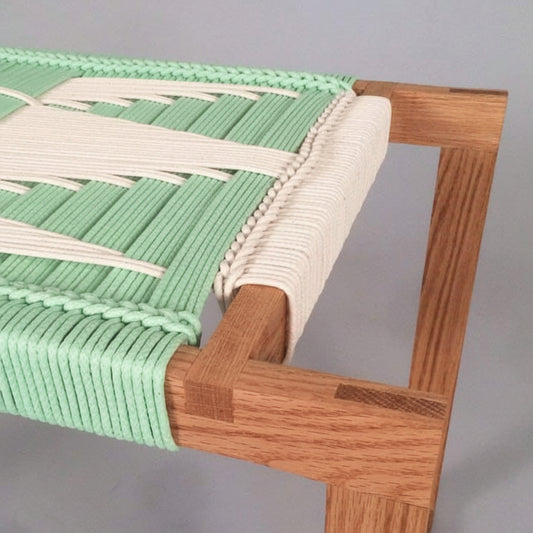 Close-up of a chair with green woven seat and wooden frame on a gray background
