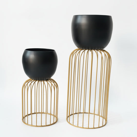 Two black planters on gold wire stands against a white background