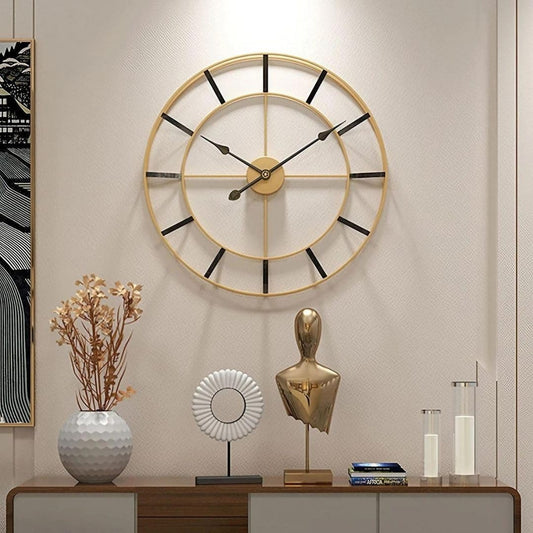 Decorative wall clock with a vase, sculpture, and books on a shelf against a beige wall.