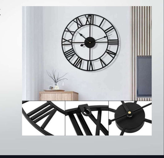 Large black wall clock with Roman numeral design on a white wall.