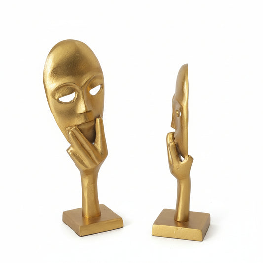Two gold-colored sculptures of abstract human figures on a white background