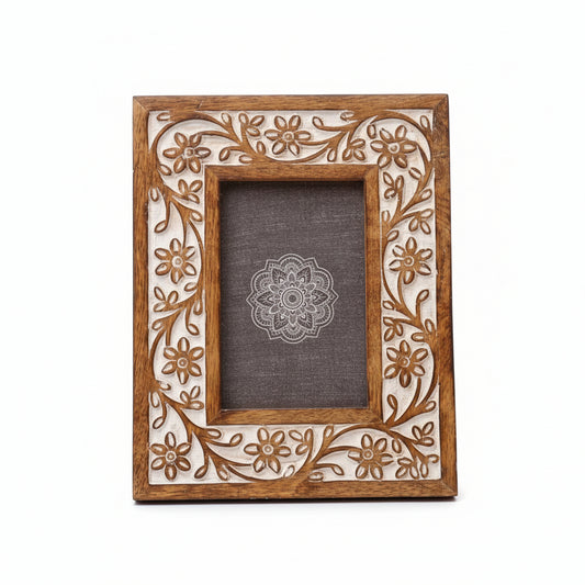 Wooden photo frame with floral carvings on a marble surface