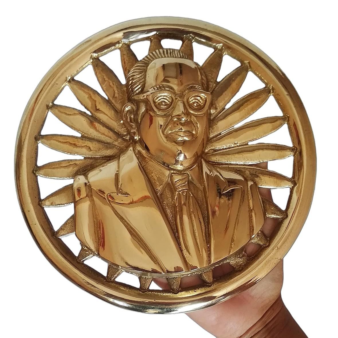 Gold circular decorative item with a portrait inside, held by a hand against a white background
