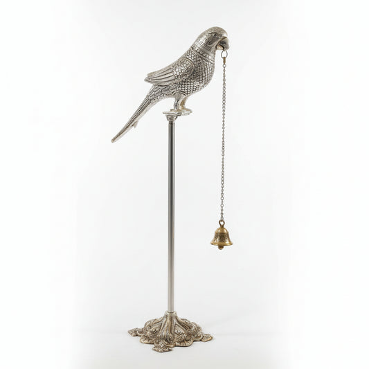 Decorative silver parrot figure on a stand with a chain and bell against a light background