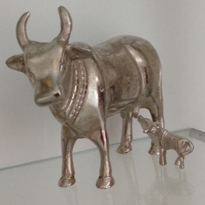 Metallic bull figurine on a reflective surface with a plain background