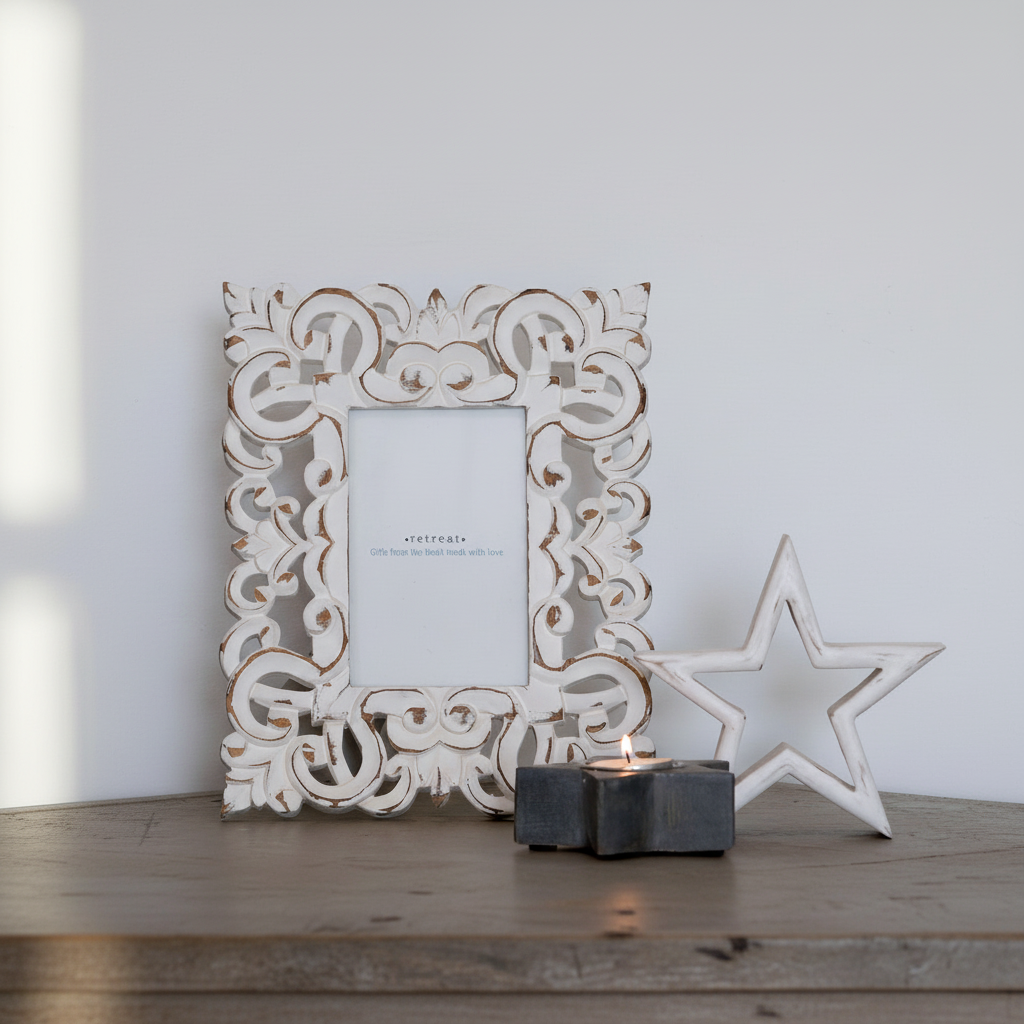 Decorative white frame with intricate patterns on a wooden surface with a star and candle.