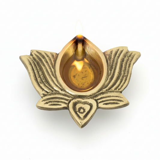 Brass lotus-shaped oil lamp with a lit wick on a white background