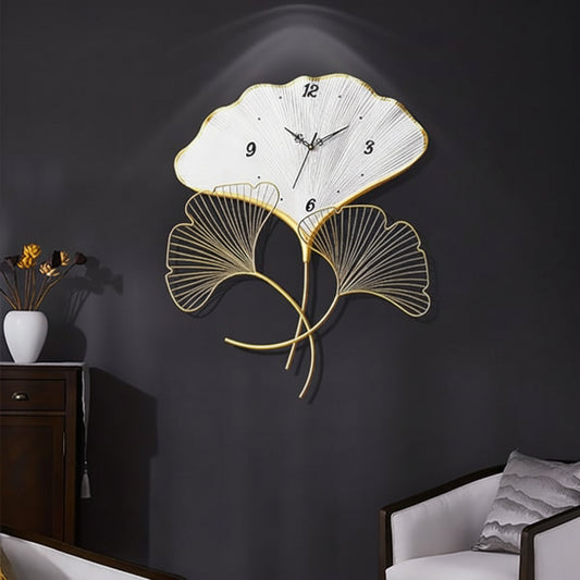 Decorative wall clock with leaf design on a dark wall