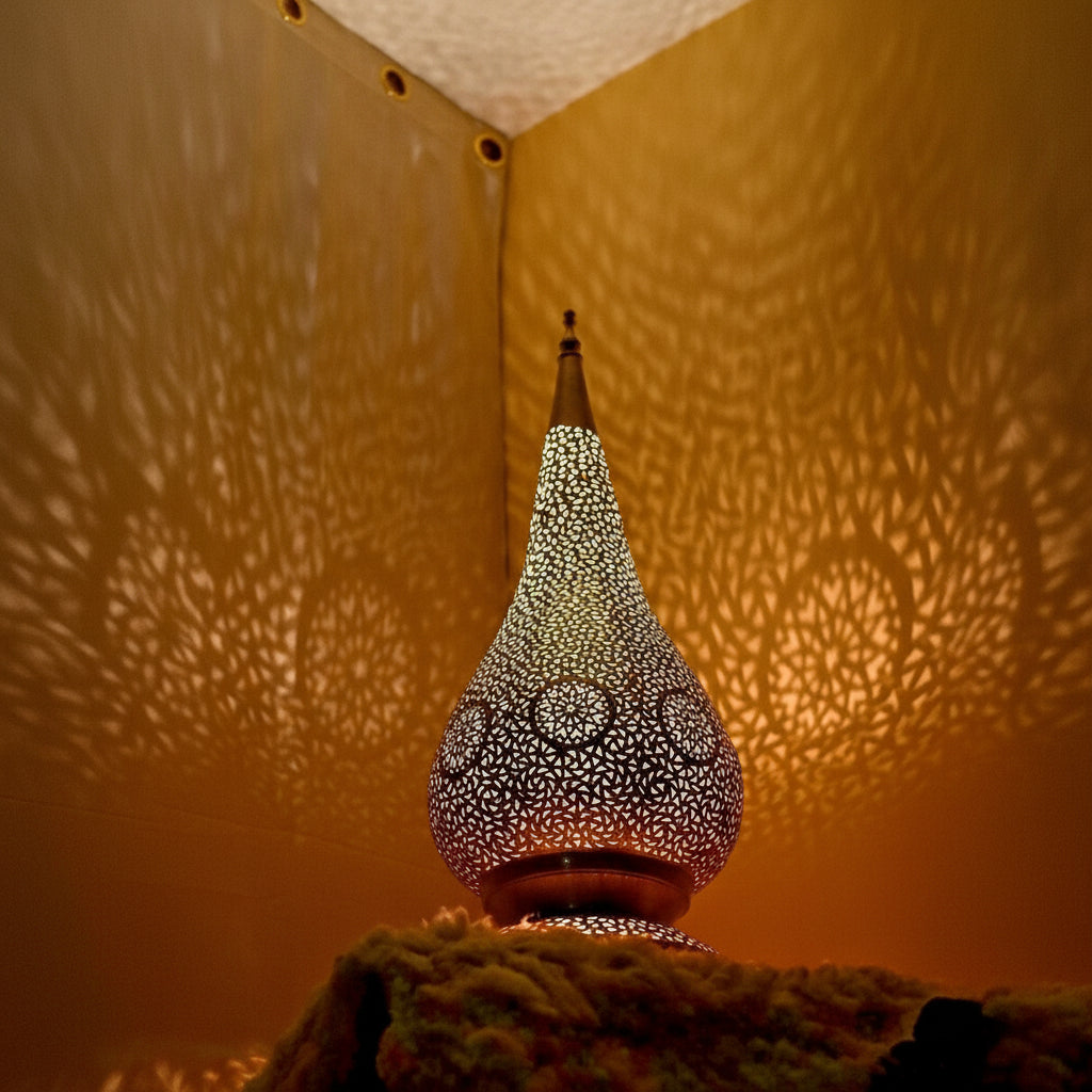 Decorative lamp with intricate design casting shadows on a textured wall.