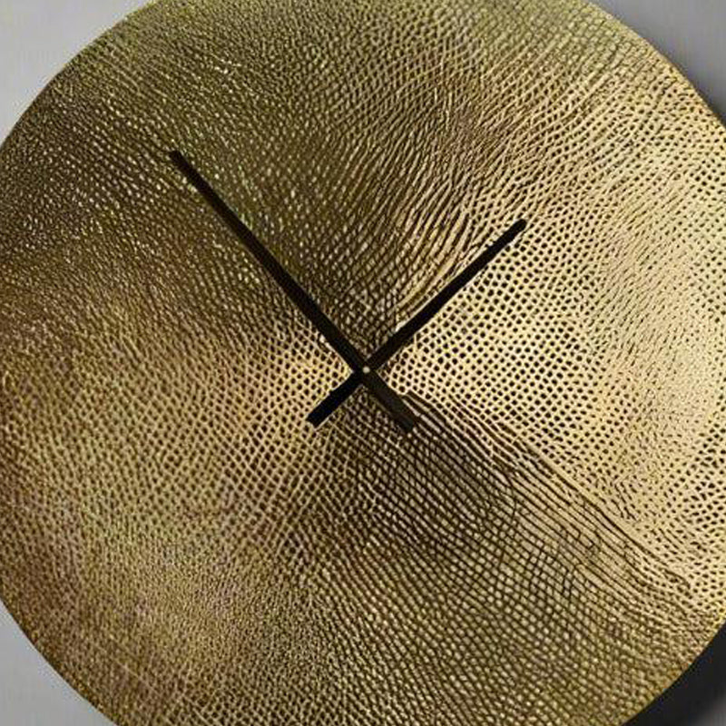 Gold textured wall clock with black hands on a light gray background