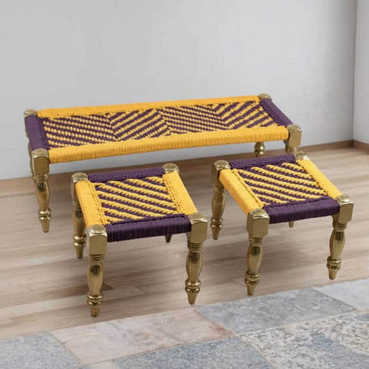Woven bench and stools with yellow and purple pattern on a wooden floor.