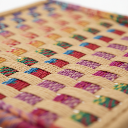 Close-up of a woven mat with colorful square patterns on a white background