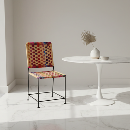 Colorful chair next to a white table with a vase and plant in a minimalistic setting