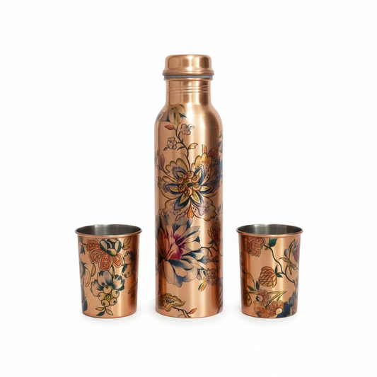 Copper water bottle and two copper cups with floral designs on a white background
