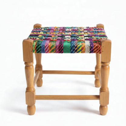 Wooden stool with a colorful woven seat on a marble floor.
