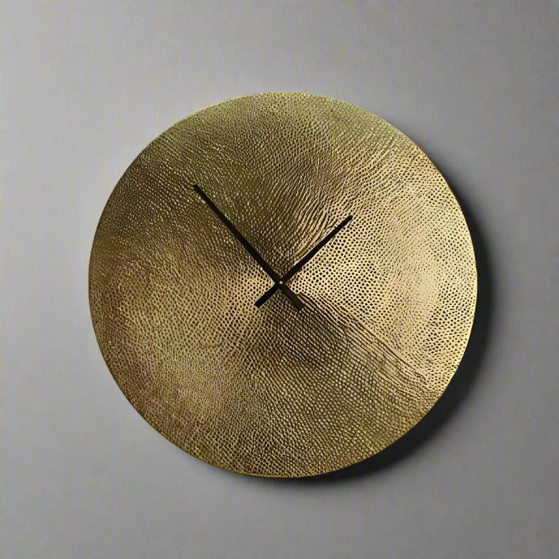 Gold wall clock with textured surface on a gray background