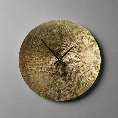 Gold wall clock with textured surface on a gray background