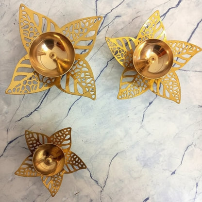 Three gold decorative items with intricate cut-out designs on a marble surface