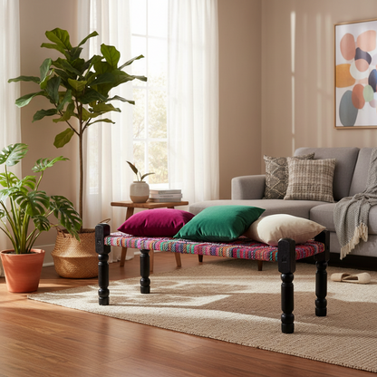 Living room with a colorful bench, gray sofa, and decorative plants.