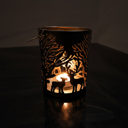 Decorative candle holder with cut-out designs of deer and trees, illuminated from within.
