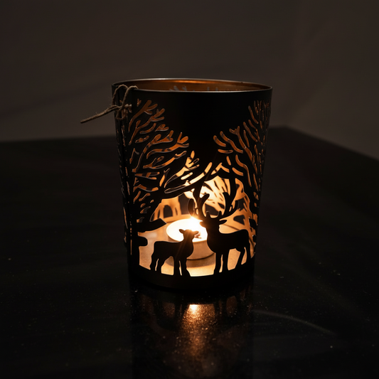 Decorative candle holder with cut-out designs of deer and trees, illuminated from within.
