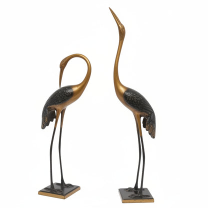 Two bronze cranes on stands against a white background