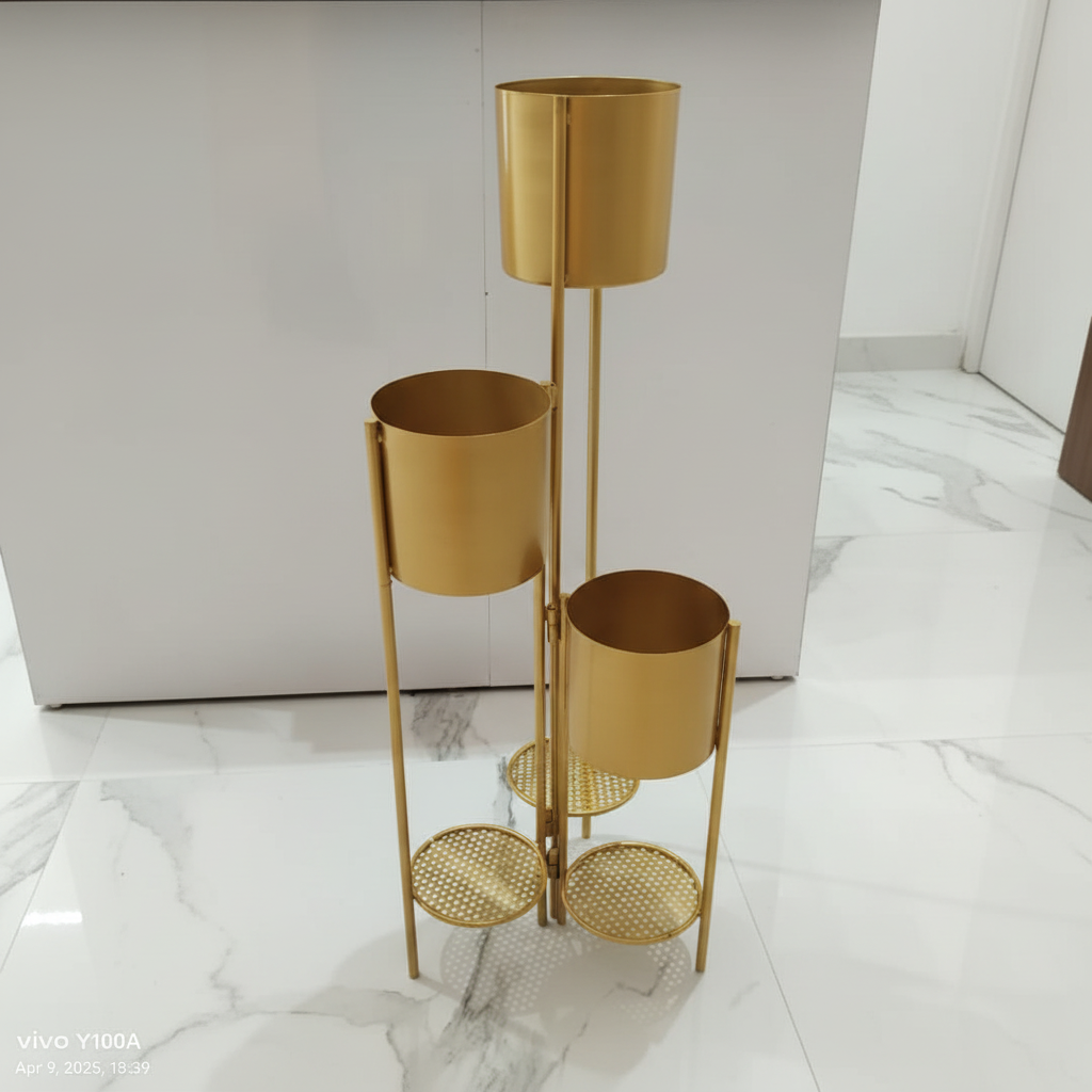 Gold metal plant stand with three cylindrical shelves on a white background