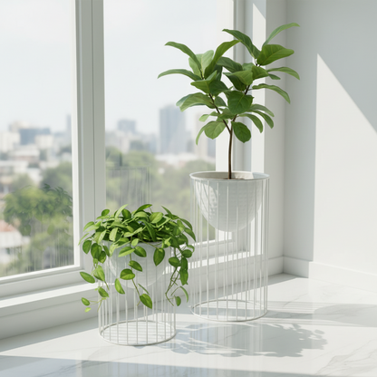 Two potted plants on a windowsill with a cityscape view outside.