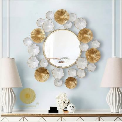Decorative wall mirror with gold and white floral elements on a light blue wall.