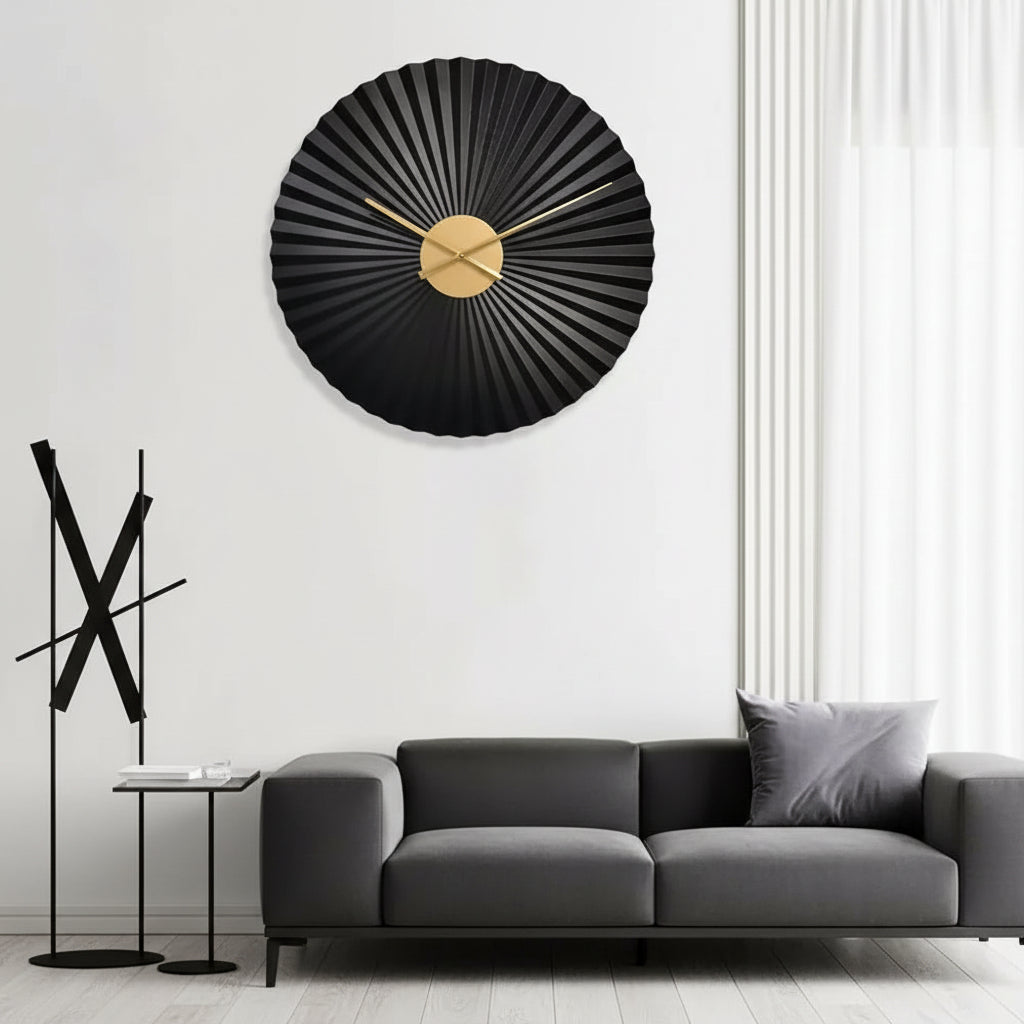Decorative wall clock with black and gold design on a white wall above a gray sofa.