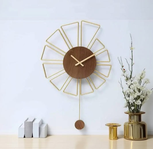 Decorative wall clock with wooden face and gold metal frame on a white wall.