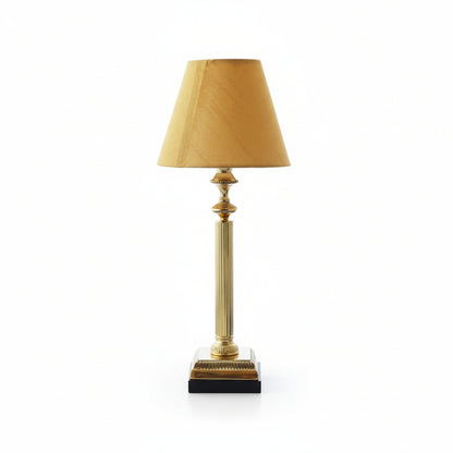 Table lamp with gold base and beige shade on a white background