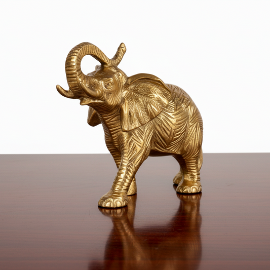 Gold elephant figurine on a reflective surface with a white background