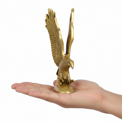 Gold eagle statue held in a hand against a white background