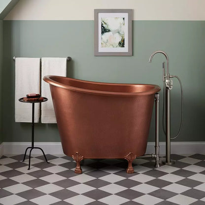 Copper bathtub in a bathroom with checkered floor and framed artwork on the wall.