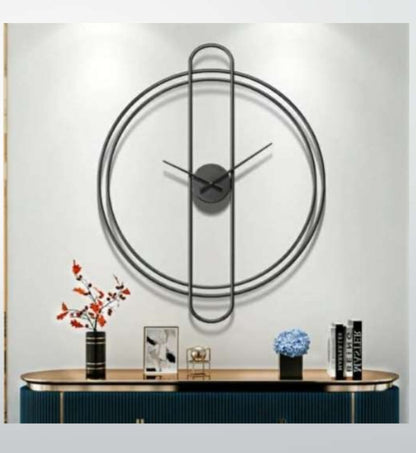 Modern wall clock with decorative items on a console table against a white wall.