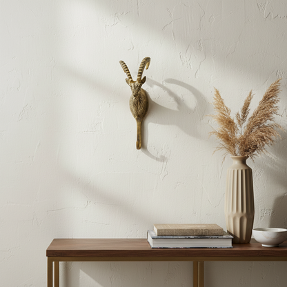 Decorative wall piece with antlers and a vase with dried plants on a wooden table against a textured wall.