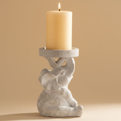 Decorative candle holder shaped like a elephant with a lit candle on a beige background