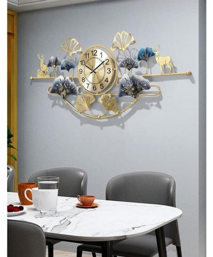 Decorative wall clock with floral and deer design on a gray wall above a dining table.
