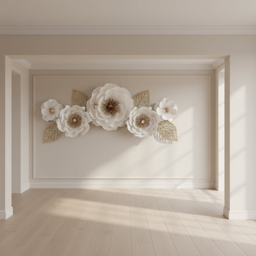 Decorative wall art with white paper flowers and gold leaves on a gray wall.