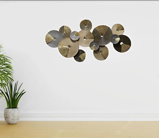 Decorative wall art with circular metal pieces on a white wall, accompanied by a potted plant.