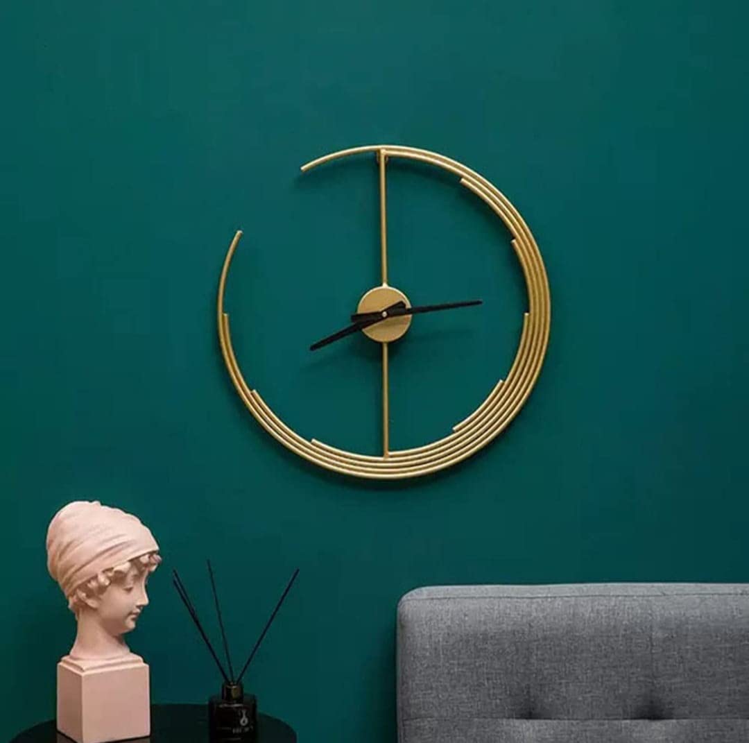 Gold wall clock on a teal wall with a gray sofa and pink bust in the foreground.
